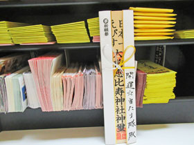 宝くじ封入作業で大前恵比寿神社の御札を掲げて作業中